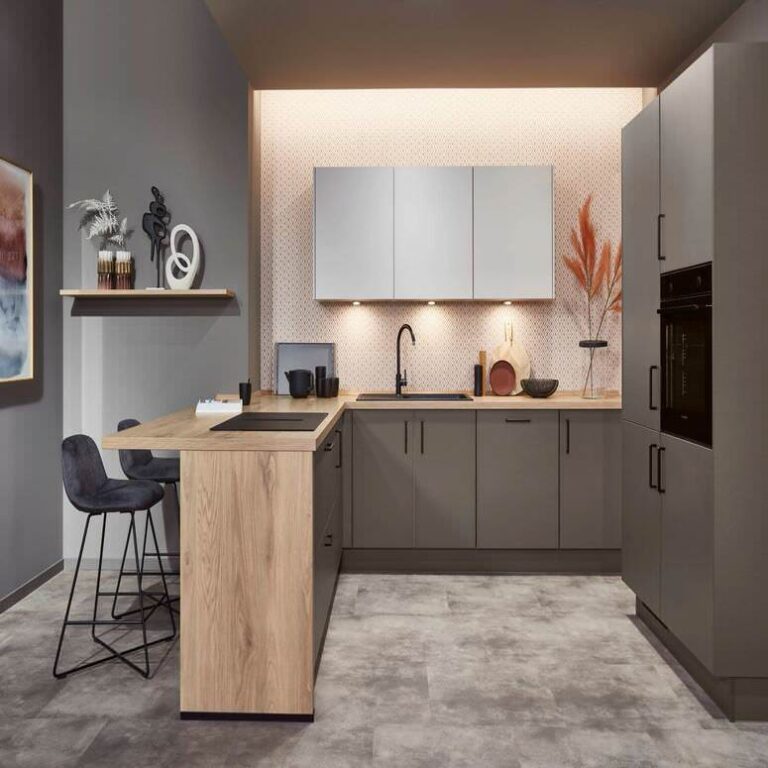 Exklusive U-Küche mit Holztresen – Küchenstudio Oberhausen Exklusive U-Küche in Grau mit Tresen aus Holz, Barhockern und indirekter Beleuchtung
